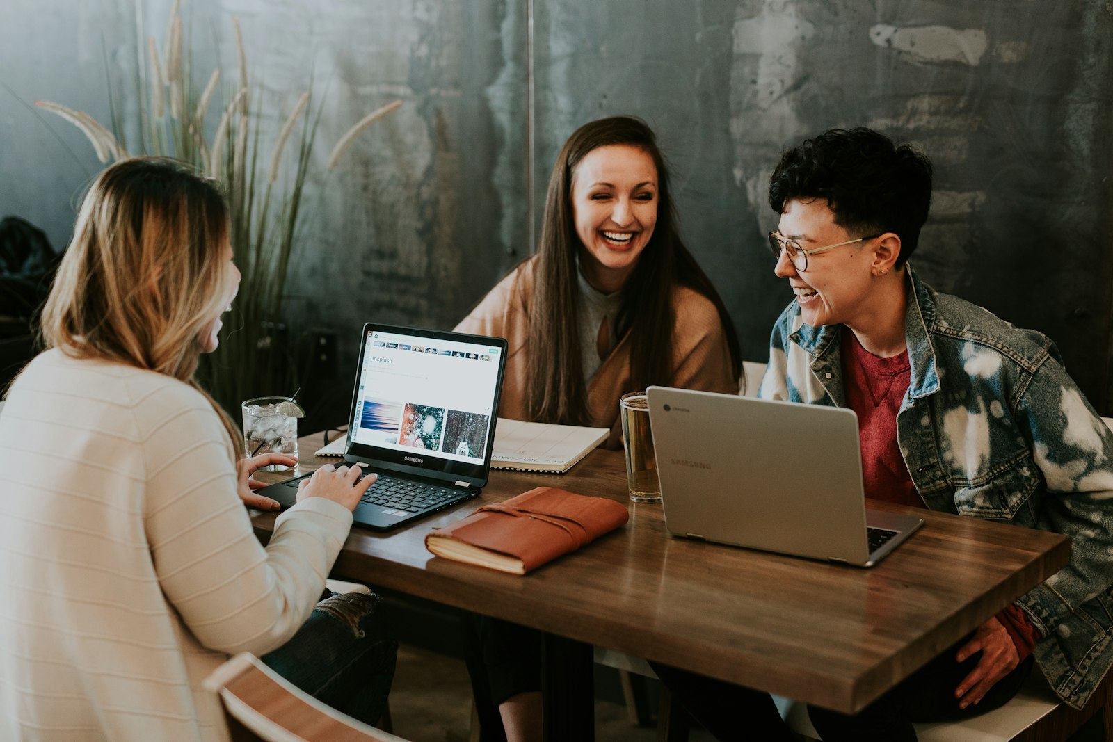 People working together at a table with notebooks and laptops.