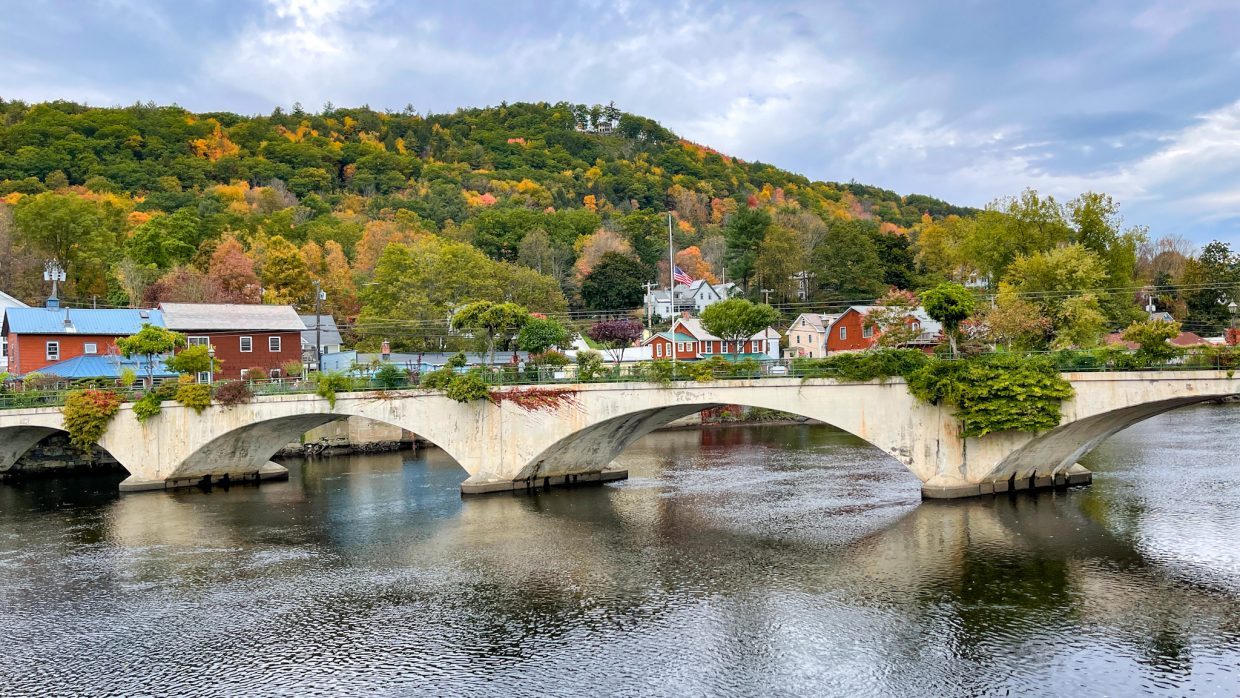 The Bridge of Flowers crossing the Deerfield River in Shelburne Falls, Massachusetts, with autumn hills beyond.
